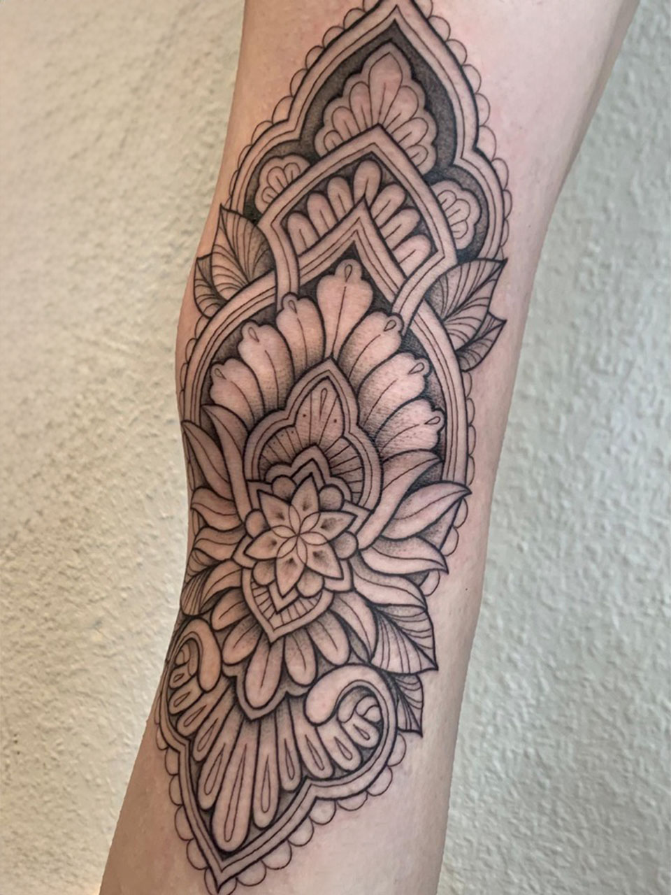 tatuaje ornamental detrás de la rodilla en negro linea fina y linea gruesas